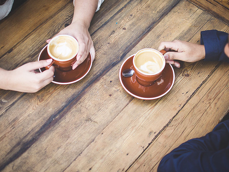 A couple's hands holding coffee cups while they are having a break up conversation.