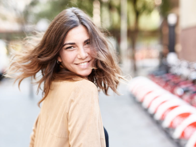 A woman doing a turn on the street dressed nice for a date.