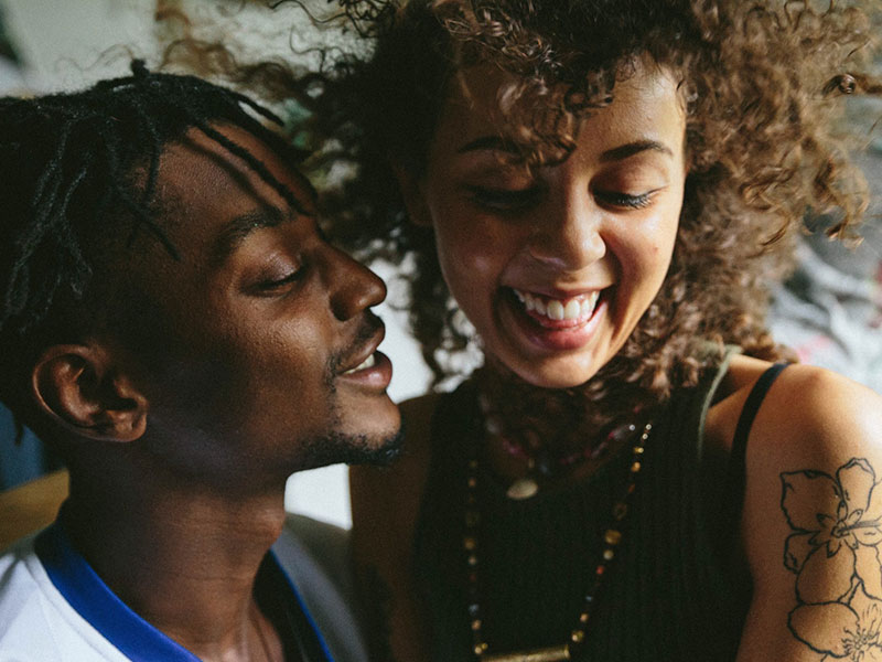 A guy talking to a woman who's laughing with him.