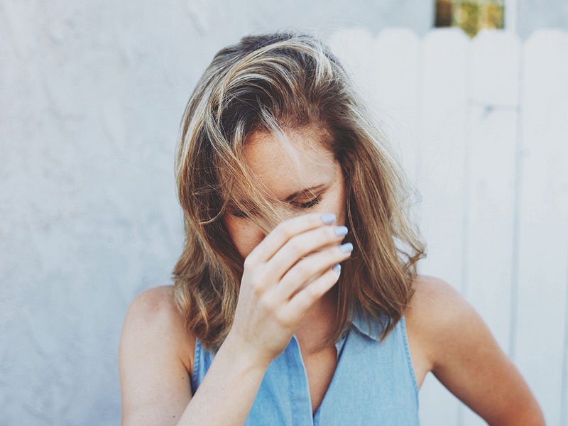 A woman who's feeling trapped in a relationship covering her face and thinking things through.