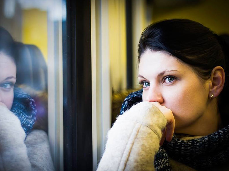 A women wondering how to know when to break up with someone looking out the window and thinking.