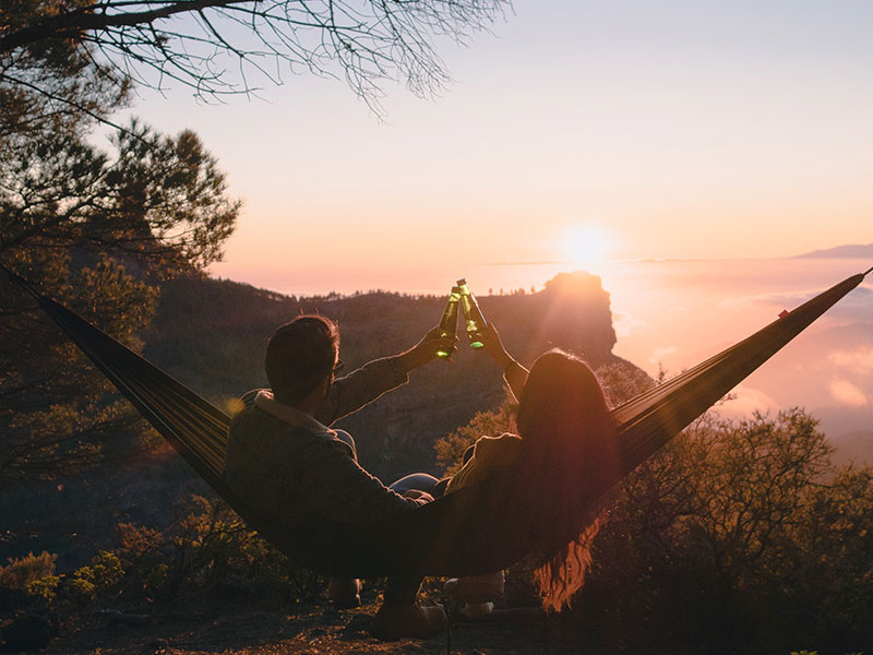 This couple in a hammock cheersing each other found great couples vacation spots on their trip.