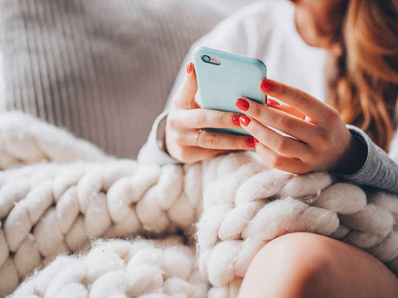 This woman updating her dating profile on her phone used these online dating profile examples to attract men to improve her profile.