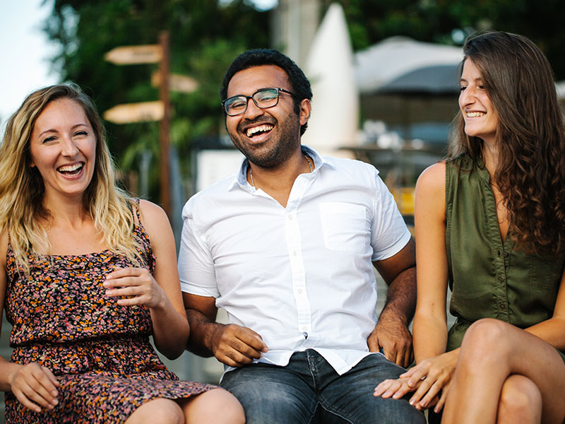 A guy laughing with his girlfriend and her friends who he's meeting for the first time.