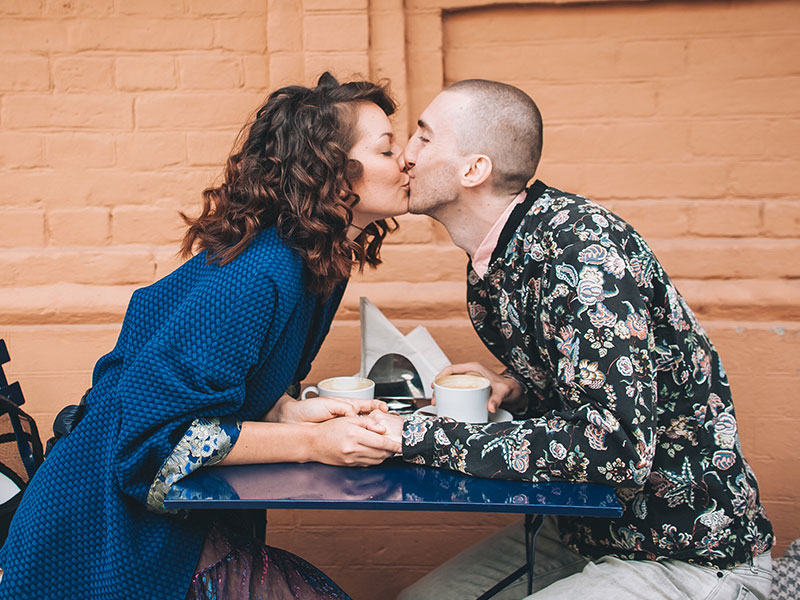 A woman who used to have a lot of bad dates, kissing her date across the table.
