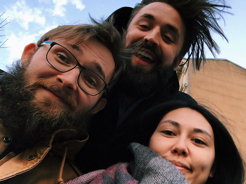 A man who's wondering if he's a unicorn in a polyamorous relationship smiling with his two other partners as they take a selfie.