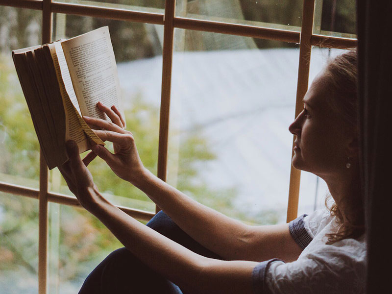 A woman reading one of these books to read after a break up and smiling.