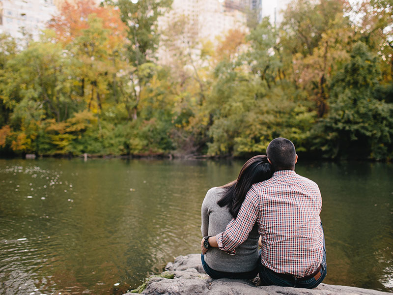 A couple dating after divorce at 40 leaning against each other as they look at a beautiful lake.