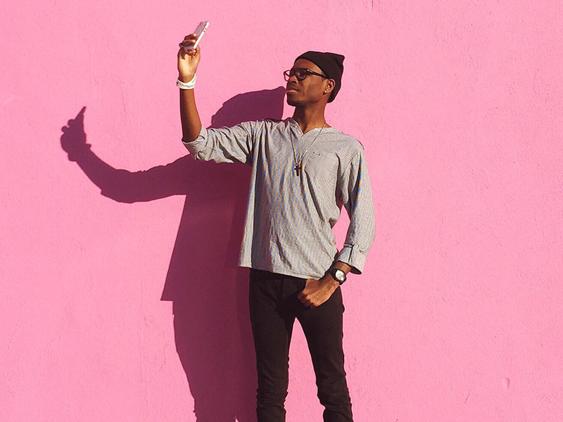 A guy standing against a pink background dating dating profile photos for his dating profile.