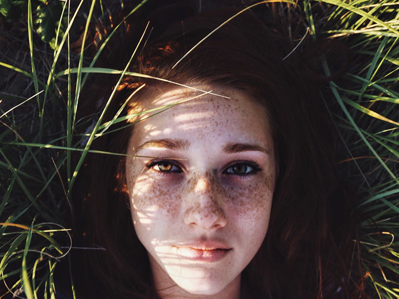 A woman who's going through a breakup in a field thinking.