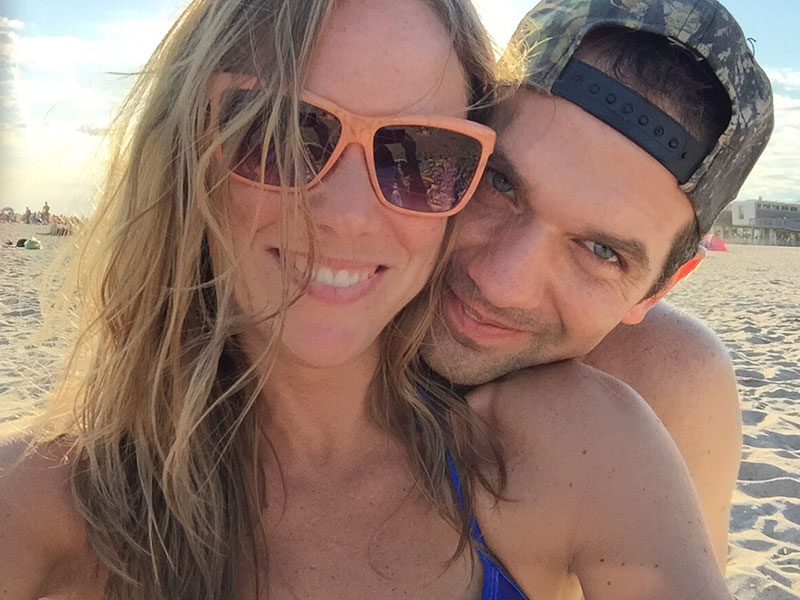 A girl who's dating a shy guy, smiling as her boyfriend grins next to her with his head on her shoulder.