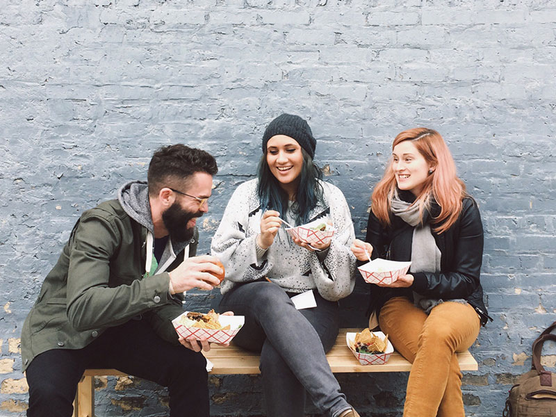 A woman and her new boyfriend meeting her friend as they all laugh and talk over lunch.