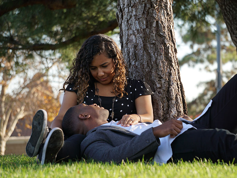 A couple who knows how to be good at communication in relationships, chatting outside in the grass.