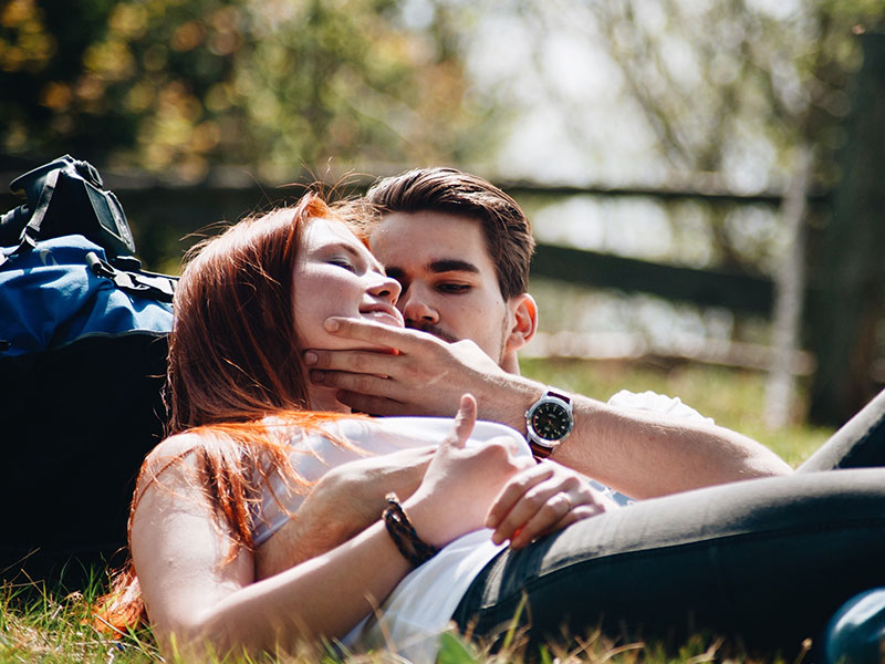 A girl wondering "Does he think about me" while sitting with him in the grass and flirting.