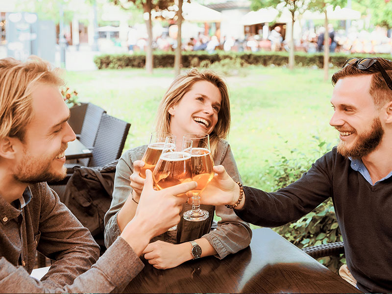 A couple who follows their own set of open relationship rules cheersing drinks with another friend at the bar.