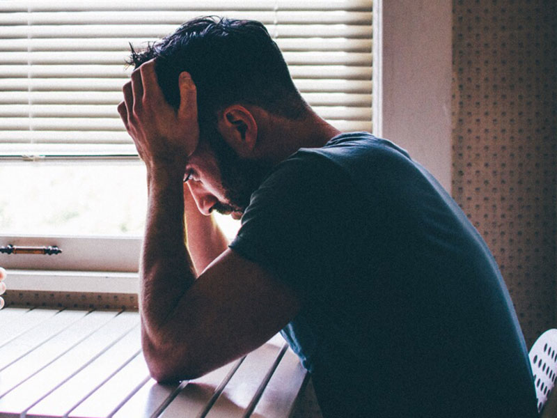 A guy who knows what it means to sabotage relationships, sitting in his kitchen with his head in his hands.