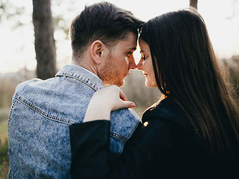 A woman who loves a man hugging him outside.