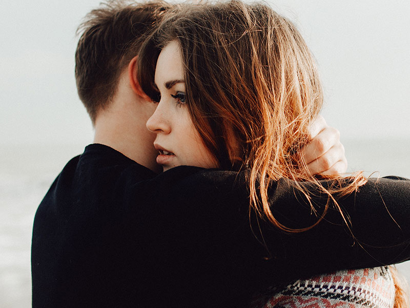 A woman wondering, can you talk to me? while hugging her boyfriend who refuses to talk.