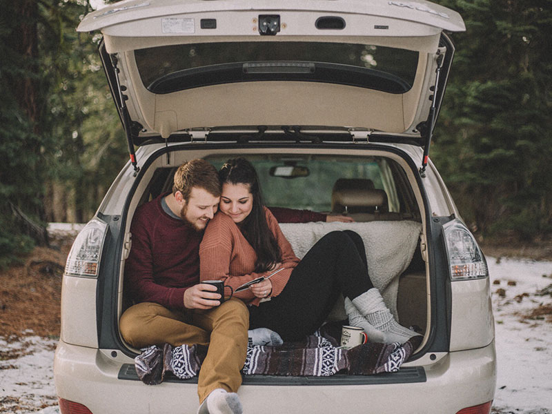 A man who listened to this first date tips, making his date laugh as they sit in the trunk of his car.