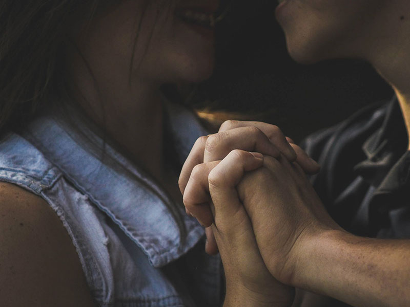 A couple who worked hard at getting back together with an ex, holding hands and kissing intensely.