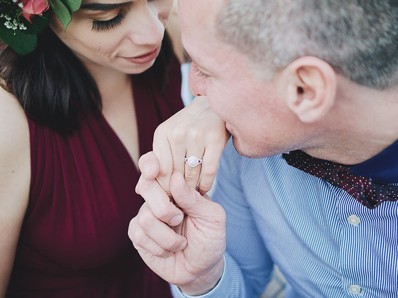 A woman who has high standards, at her engagement having her hand kissed by her fiance.