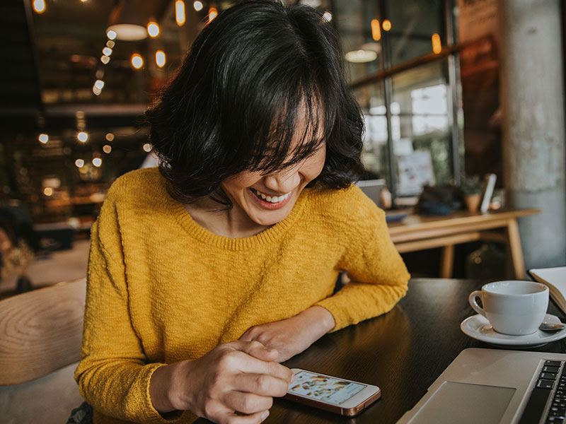 A woman accepting a message from a guy who learned how ot slide into dms without freaking her out, laughing at her phone and texting.