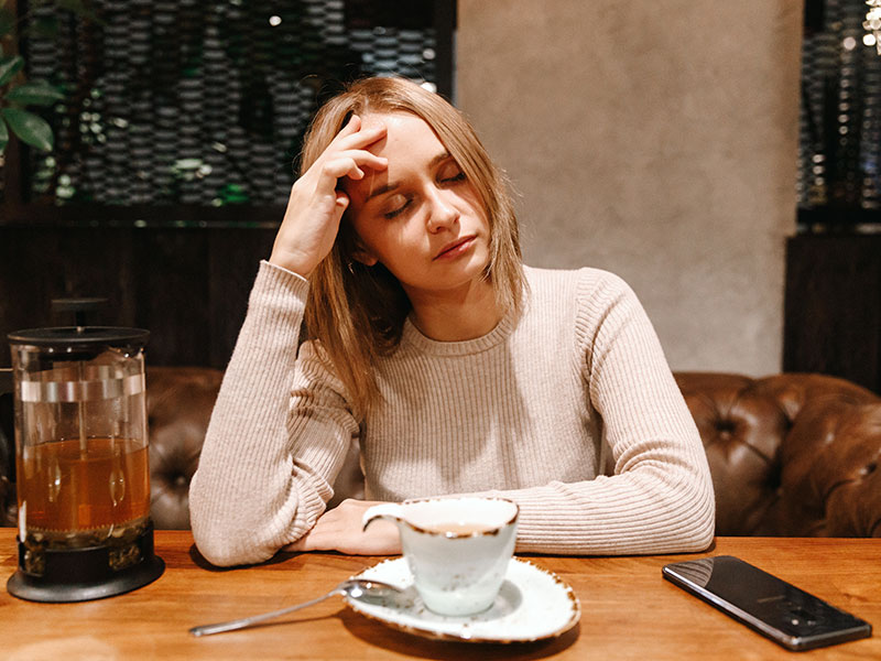 A woman who's getting the silent treatment abuse from her partner looking upset and stressed out at the dinner table.