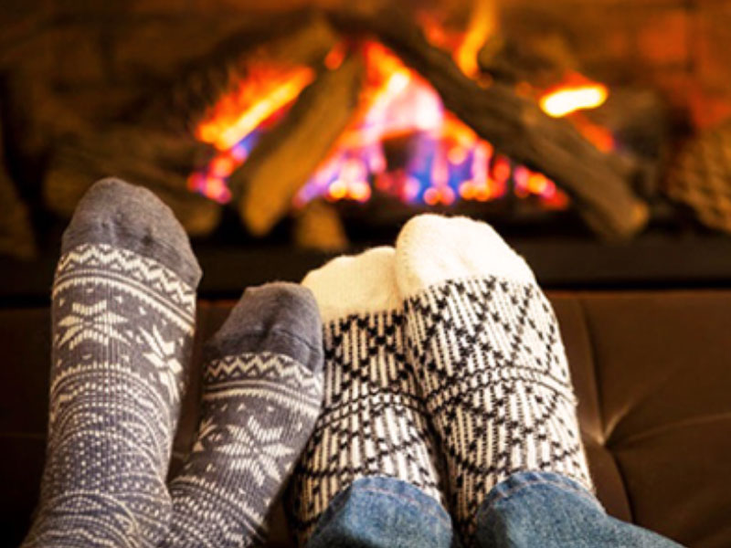 A couple who took one of these winer date ideas and are snuggling up in front of the fire.