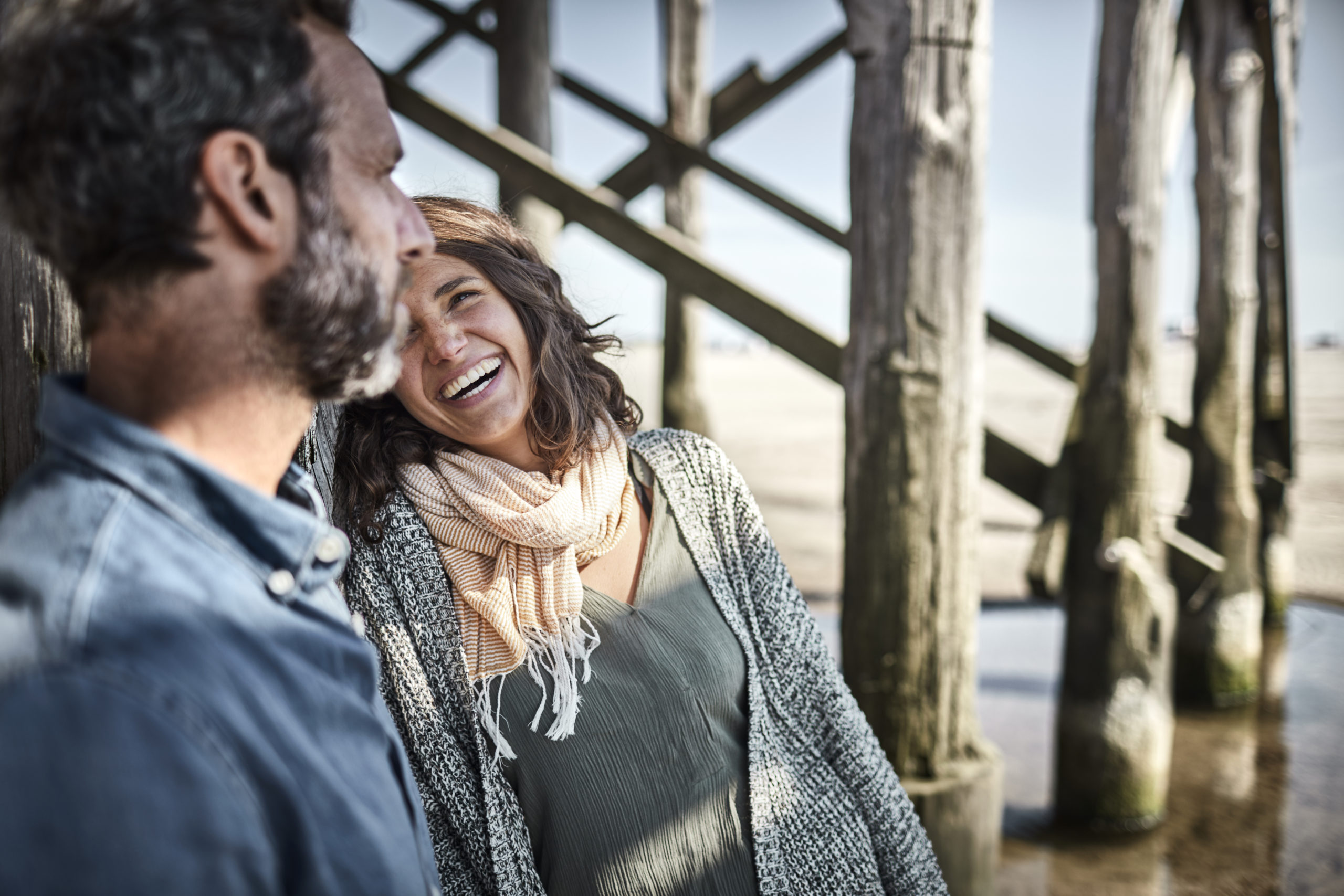 Man and smiling woman talking at stilt house on the beach as woman tells the man she likes him.