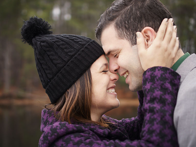 A woman who knows what it's like being single at 40, laughing and she leans against her boyfriend before they kiss.