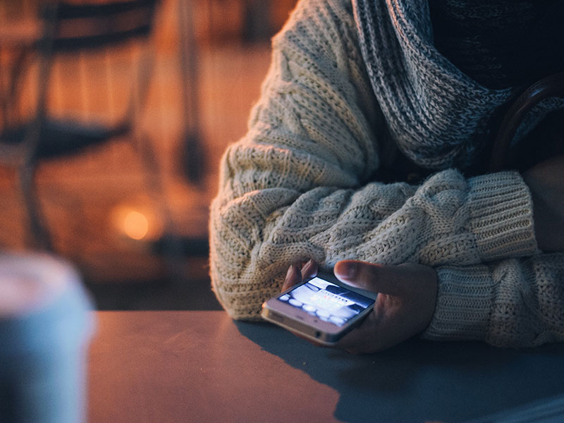 A girl at a bar double texting a guy.