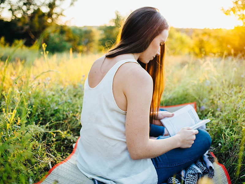 A woman getting over a crush, reading her journal in a field.