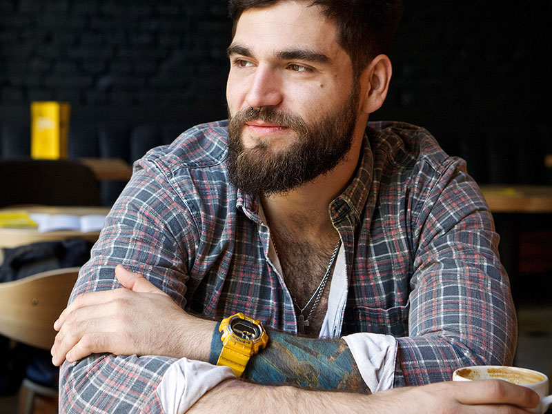 A confident man who shows a lot of the qualities of a good man, sitting at a coffee shop looking out a window.