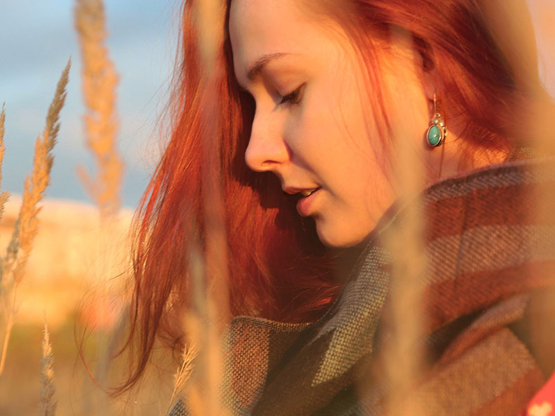 A woman who thinks she's being gaslighted in her relationship thinking about the signs of gaslighting while in a filed wondering what to do.