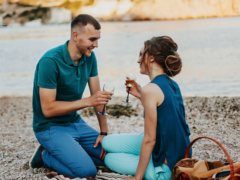 A man and a woman on their first date, having a picnic on the beach and wondering what comes after the first date.