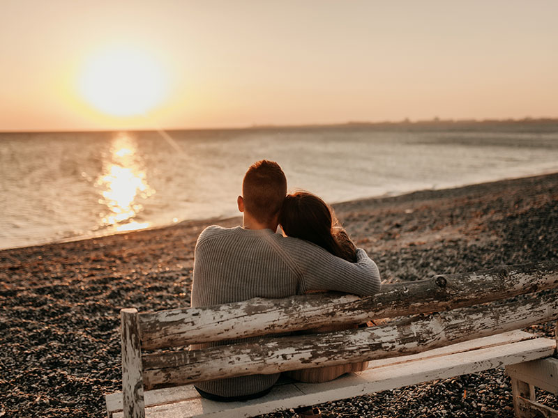 A couple who used one of these date night ideas for married couples, watching the sunset on the beach.