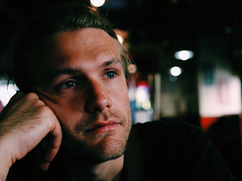 A man going through a divorce, at the bar sipping a drink and thinking.