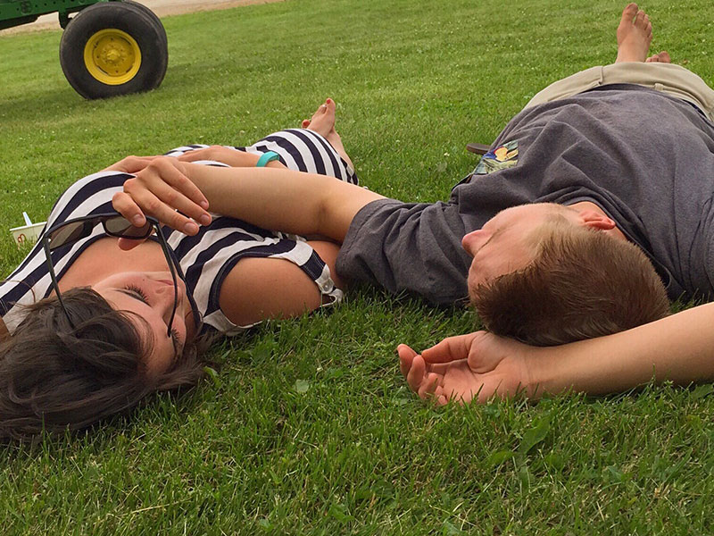 A woman lying the grass with her friend, thinking to herself, "I'm in love with my best friend."