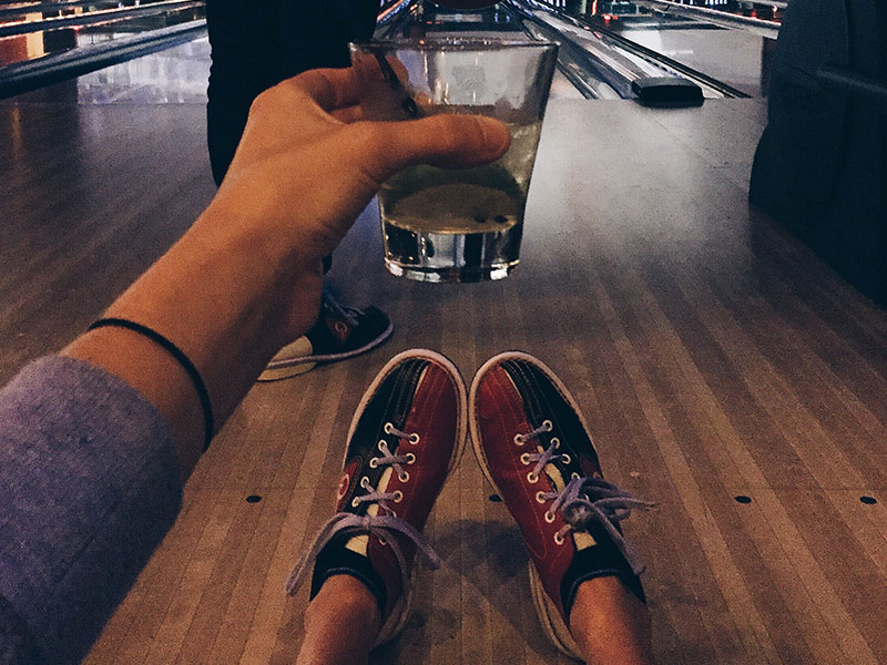 A guy drinking while bowling, using one of these indoor date ideas.