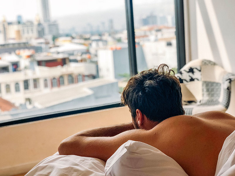 A man in bed looking out the window thinking, "I miss my girlfriend."