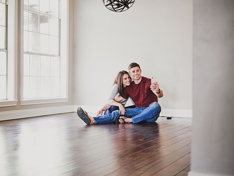 A couple moving in together taking a selfie on the floor of their new apartment.