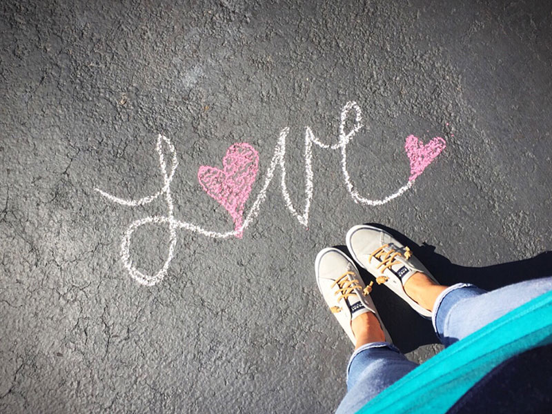 A girl looking down at her shoes and a single life quote that says love written at her feet.