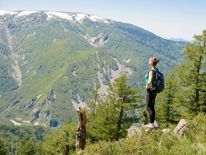 A woman who's taking time for herself after a breakup on a solo hike looking out at the view of the mountains.