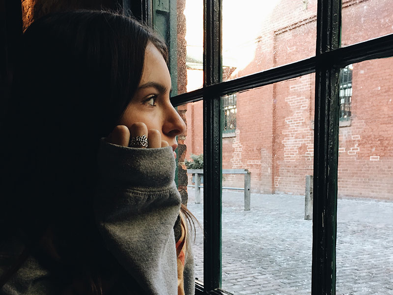 A woman looking out the window thinking about losing a friend and what she'll do next.