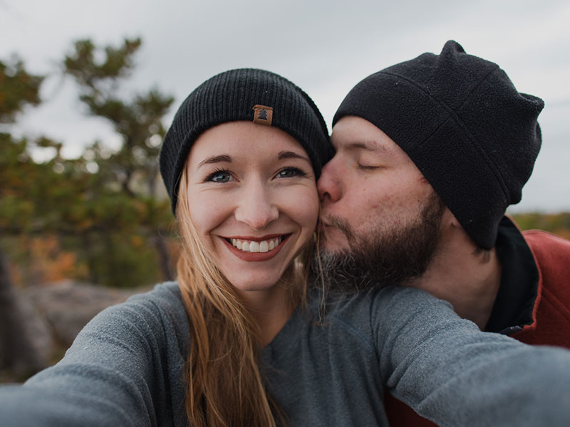A couple who used to be in a situationship, smiling as the guy kisses the girl's cheek while hiking.