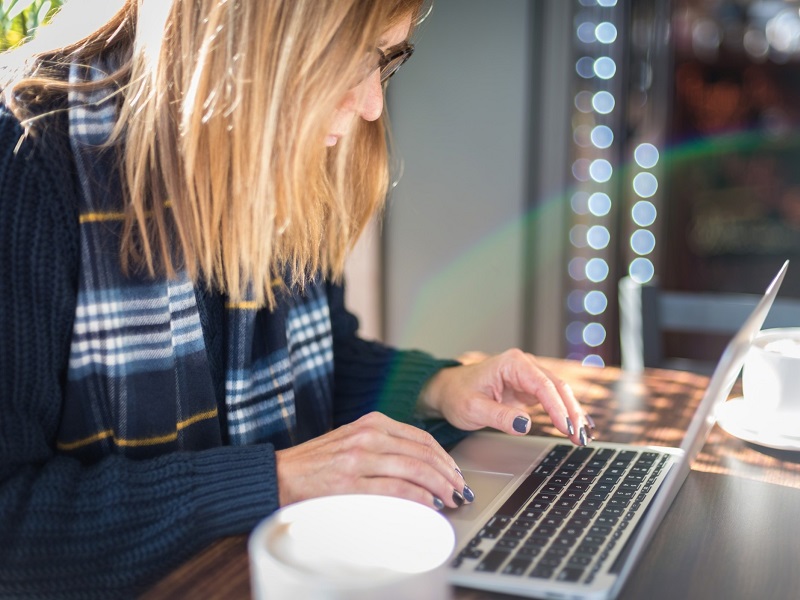 LBlonde woman typing on laptop and wondering, does online dating work?