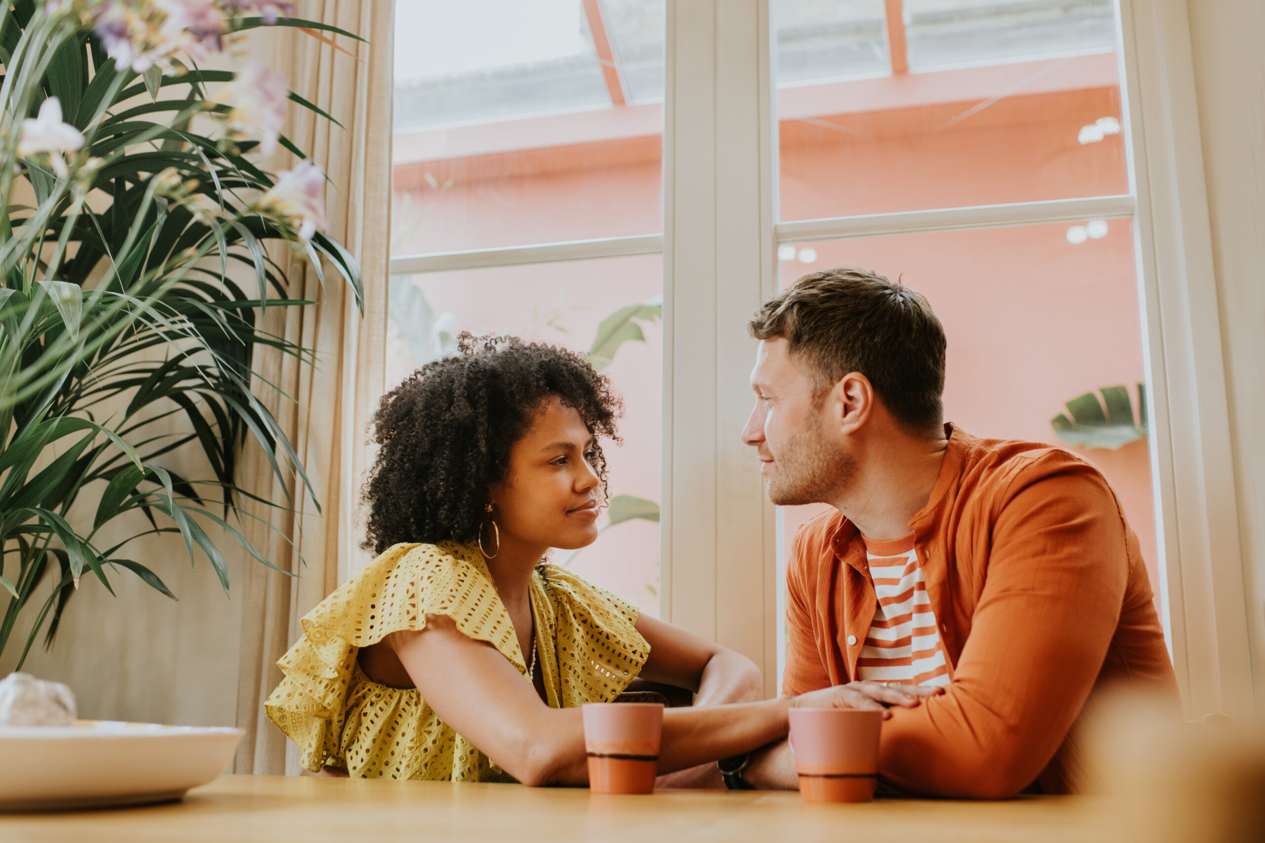 Happy, young couple sitting at a table and looking deeply into each others eyes while thinking of things to talk about on a first date.
