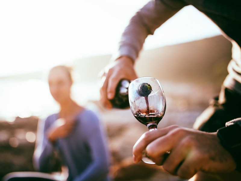 Man pouring wine on beach as a romantic idea for her