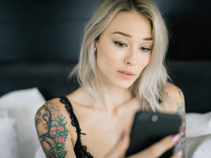 Attractive woman sitting on bed sending a sexting text