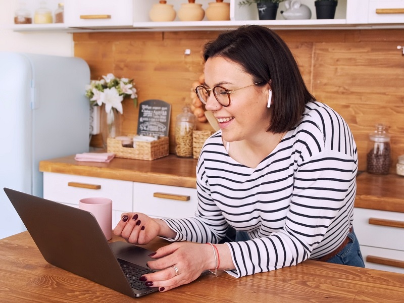 lady standing in kitchen with laptop trying out virtual date ideas